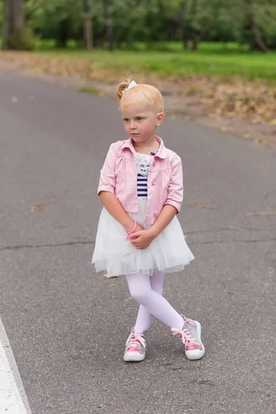 Милая маленькая девочка в красивом платье и кроссовки играют на — стоковое фото