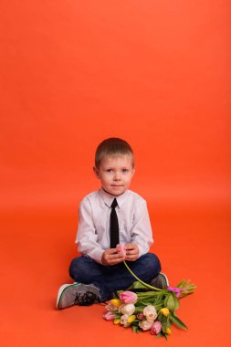Kırmızı bir arka plan üzerinde stüdyoda poz çiçekli küçük çocuk