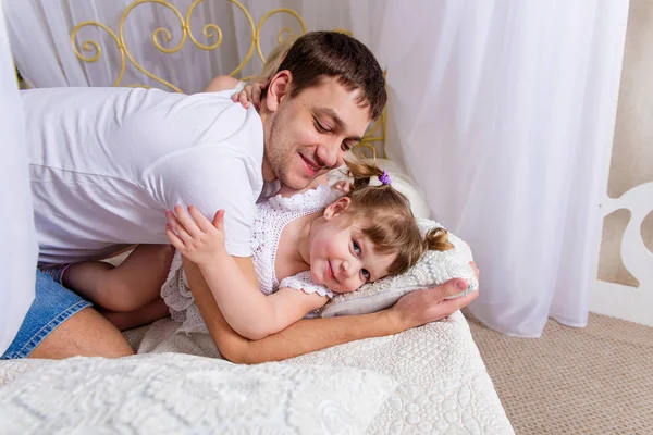 Táta a dcera hraje na posteli — Stock fotografie