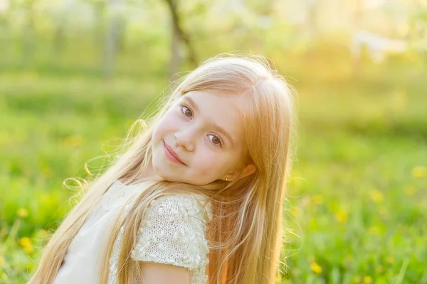 Ein hübsches kleines Mädchen läuft durch einen blühenden Garten in den — Stockfoto