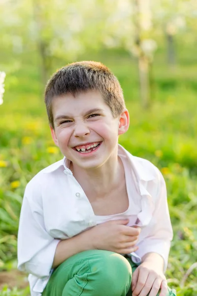 Prachtige kleine jongen in een bloeiende tuin in het voorjaar. — Stockfoto