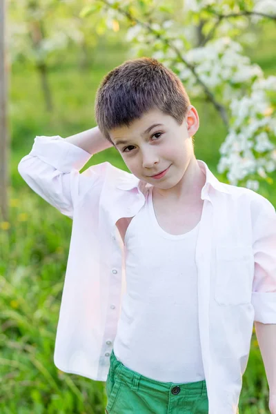 Prachtige kleine jongen in een bloeiende tuin in het voorjaar. — Stockfoto