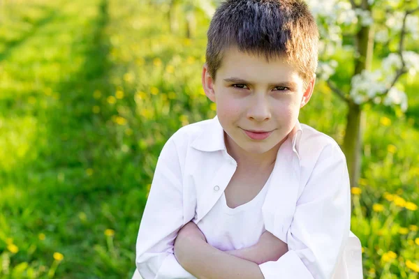 Prachtige kleine jongen in een bloeiende tuin in het voorjaar. — Stockfoto