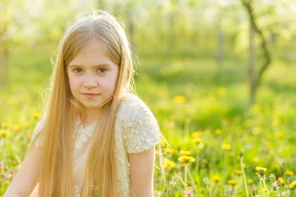 Ein hübsches kleines Mädchen läuft durch einen blühenden Garten in den — Stockfoto