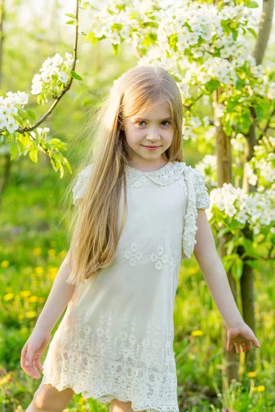 Una hermosa niña corre a través de un jardín floreciente en el s —  Fotos de Stock