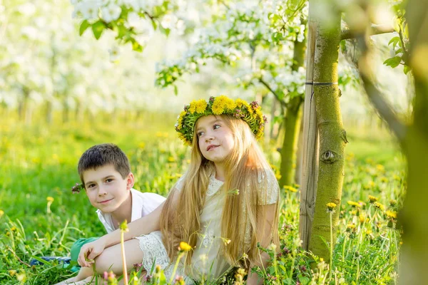 Un niño y una niña descansan en un jardín floreciente en primavera. —  Fotos de Stock