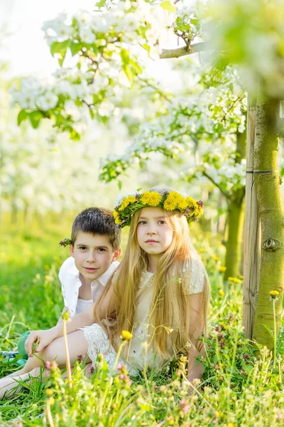 Un niño y una niña descansan en un jardín floreciente en primavera. —  Fotos de Stock
