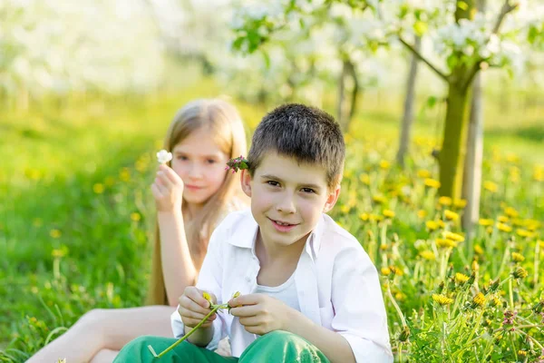 Een jongen en een meisje rusten in een bloeiende tuin in het voorjaar — Stockfoto