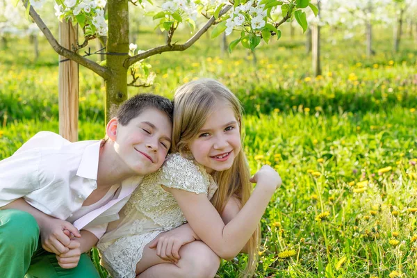 Un niño y una niña descansan en un jardín floreciente en primavera. —  Fotos de Stock
