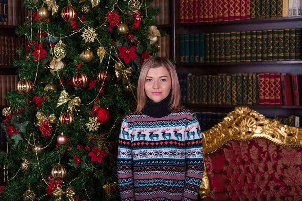 Belle fille aux cheveux blonds dans un pull près du t de Noël — Photo