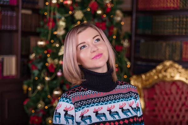 Belle fille aux cheveux blonds dans un pull près du t de Noël — Photo