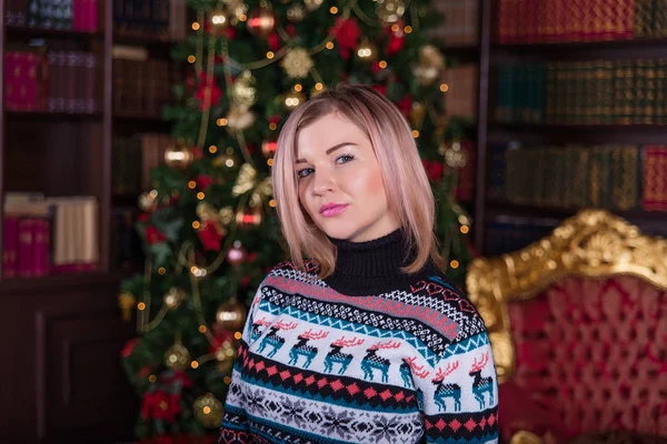 Belle fille aux cheveux blonds dans un pull près du t de Noël — Photo