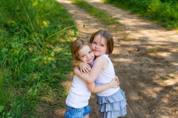 Twee kleine meisje meisje vrienden knuffelen in het bos — Stockfoto