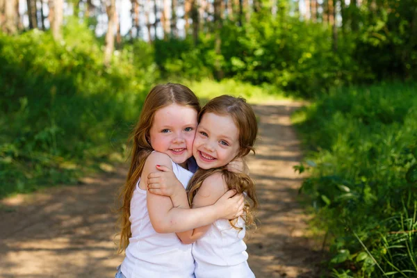 Two little girl girl friends hugging in the forest — Stock Photo, Image