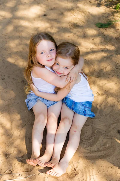 Две маленькие подружки обнимаются в лесу. — стоковое фото