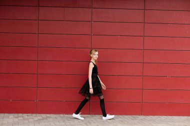 Kırmızı bir duvara poz siyah elbiseli güzel sarışın kız 