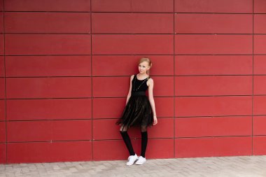 Kırmızı bir duvara poz siyah elbiseli güzel sarışın kız 