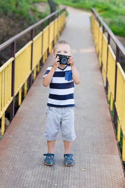 Egy kisfiú, egy régi fényképezőgéppel a kezében áll egy o — Stock Fotó