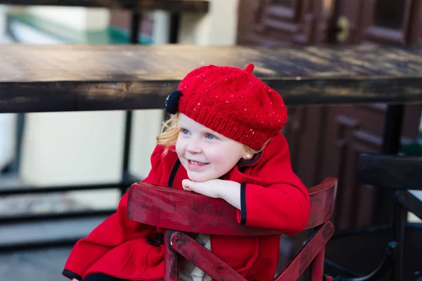 Portrait of a beautiful little girl with red hair in a red coat — Stock Photo, Image
