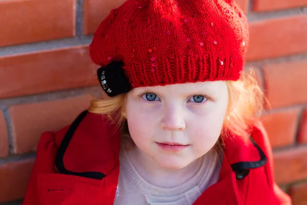 Портрет красивой маленькой девочки с рыжими волосами в красном пальто — стоковое фото
