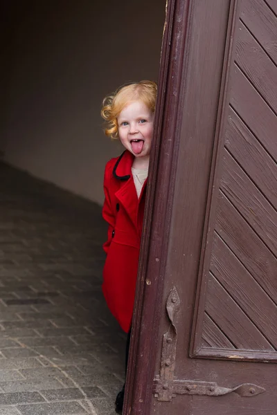 Portrait of a beautiful little girl with red hair in a red coat — Stock Photo, Image