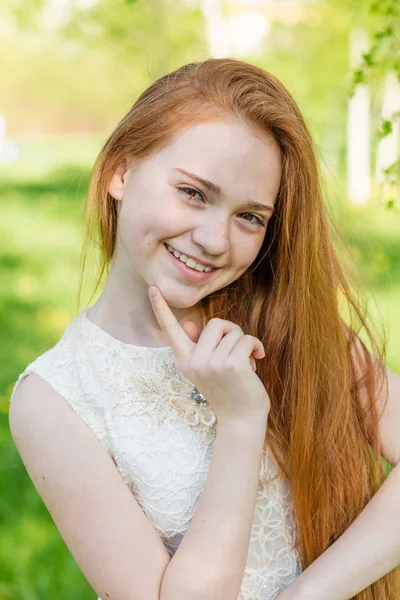 Vacker rödhårig tjej med långt hår i en park med maskrosor — Stockfoto
