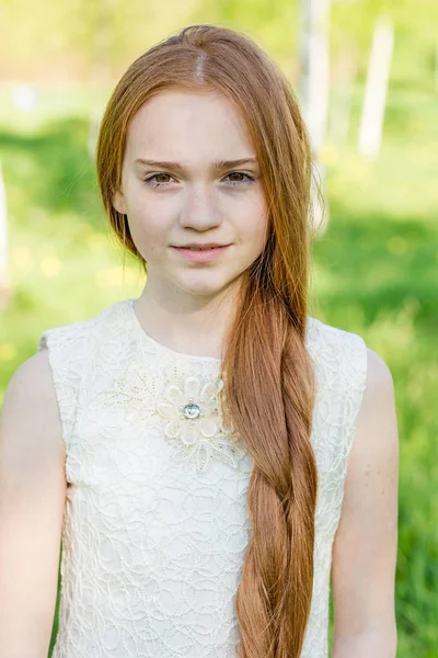 Όμορφη κοκκινομάλλα κοπέλα με μακριά μαλλιά σε ένα πάρκο με πικραλίδες — Φωτογραφία Αρχείου