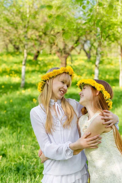 Freundinnen stehen mit Löwenzahnkränzen auf der Kopfhaut — Stockfoto