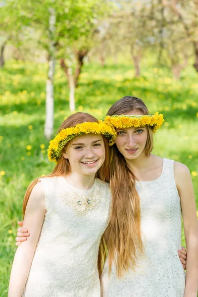 Flickvänner står med kransar av maskrosor på deras hea — Stockfoto