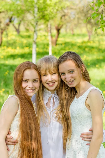 Три красивые молодые девушки в белых платьях летом — стоковое фото
