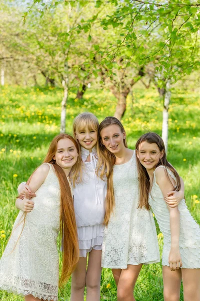 Четыре красивые молодые девушки в белых платьях летом — стоковое фото