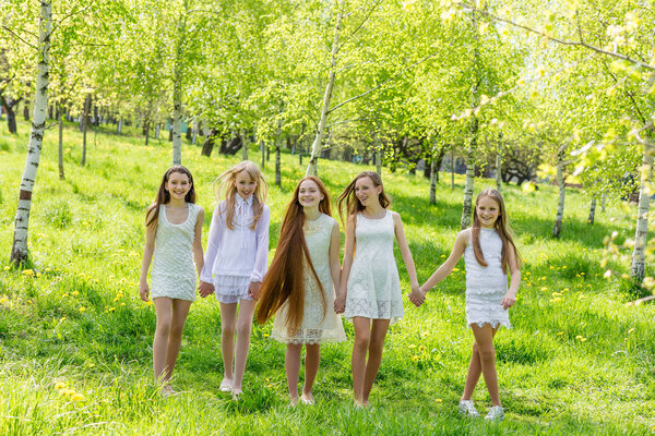 Five beautiful young girls in white dresses in summer 