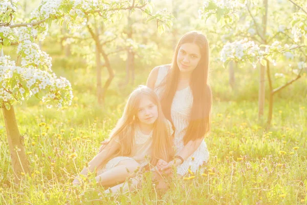 Hermosa madre e hija en un jardín floreciente en la primavera —  Fotos de Stock