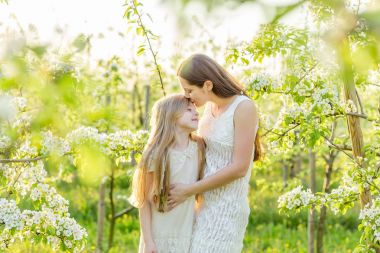 Güzel anne ve kızı ilkbaharda çiçek açan bir bahçede