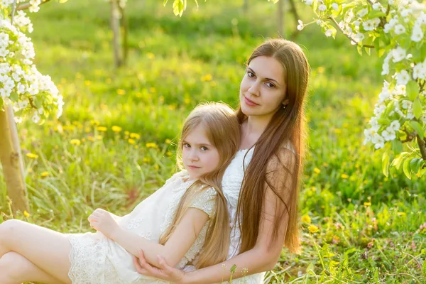 Bela mãe e filha em um jardim florescente na primavera — Fotografia de Stock