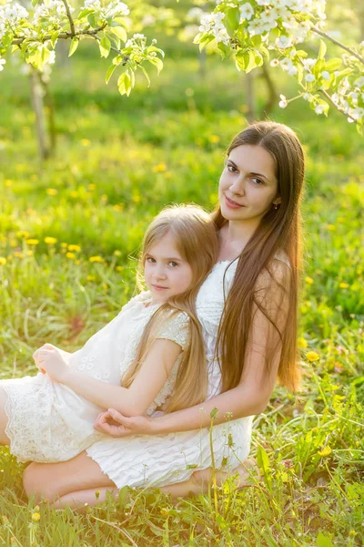 Schöne Mutter und Tochter in einem blühenden Garten im Frühling — Stockfoto