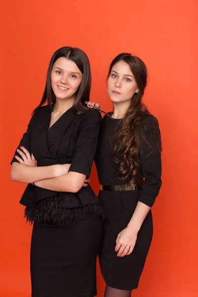 Dwa piękne młode kobiety w biznesie odpowiada na czerwonym tle — Zdjęcie stockowe