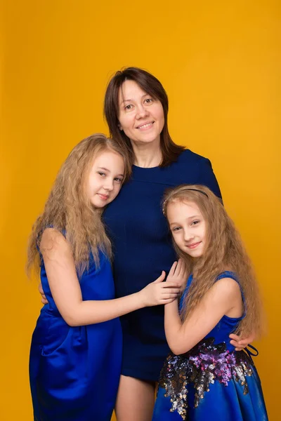 Porträt schöner Mädchen in blauen Kleidern auf gelbem Hintergrund — Stockfoto