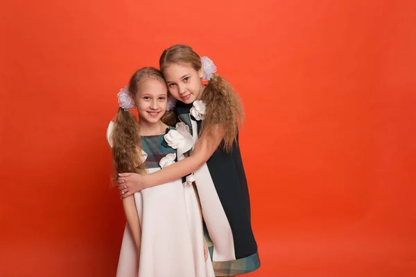 Two sisters in beautiful stylized dresses on a red background in — Stock Photo, Image