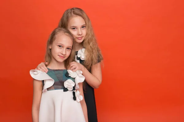 Dos hermanas en hermosos vestidos estilizados sobre un fondo rojo en — Foto de Stock