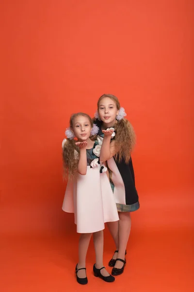 Dos hermanas en hermosos vestidos estilizados sobre un fondo rojo en — Foto de Stock