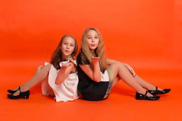 Two sisters in beautiful stylized dresses on a red background in — Stock Photo, Image