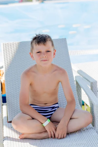 Kleiner Junge im Badeanzug auf einem Regal am Pool — Stockfoto