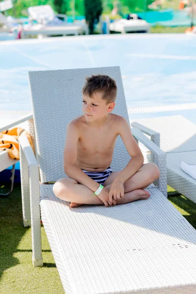 Kleiner Junge im Badeanzug auf einem Regal am Pool — Stockfoto