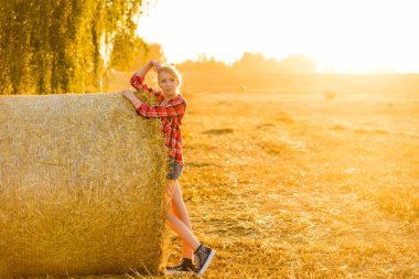 Bir alandaki saman sheaves genç kız