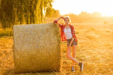 Bir alandaki saman sheaves genç kız