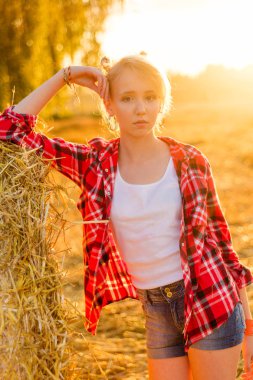 Bir alandaki saman sheaves genç kız