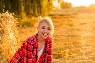 Bir alandaki saman sheaves genç kız