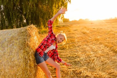 Bir alandaki saman sheaves genç kız