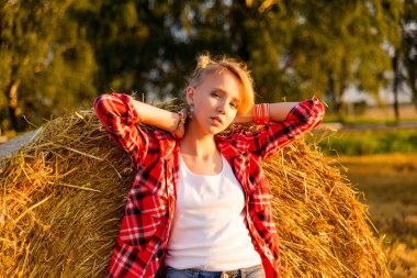Bir alandaki saman sheaves genç kız